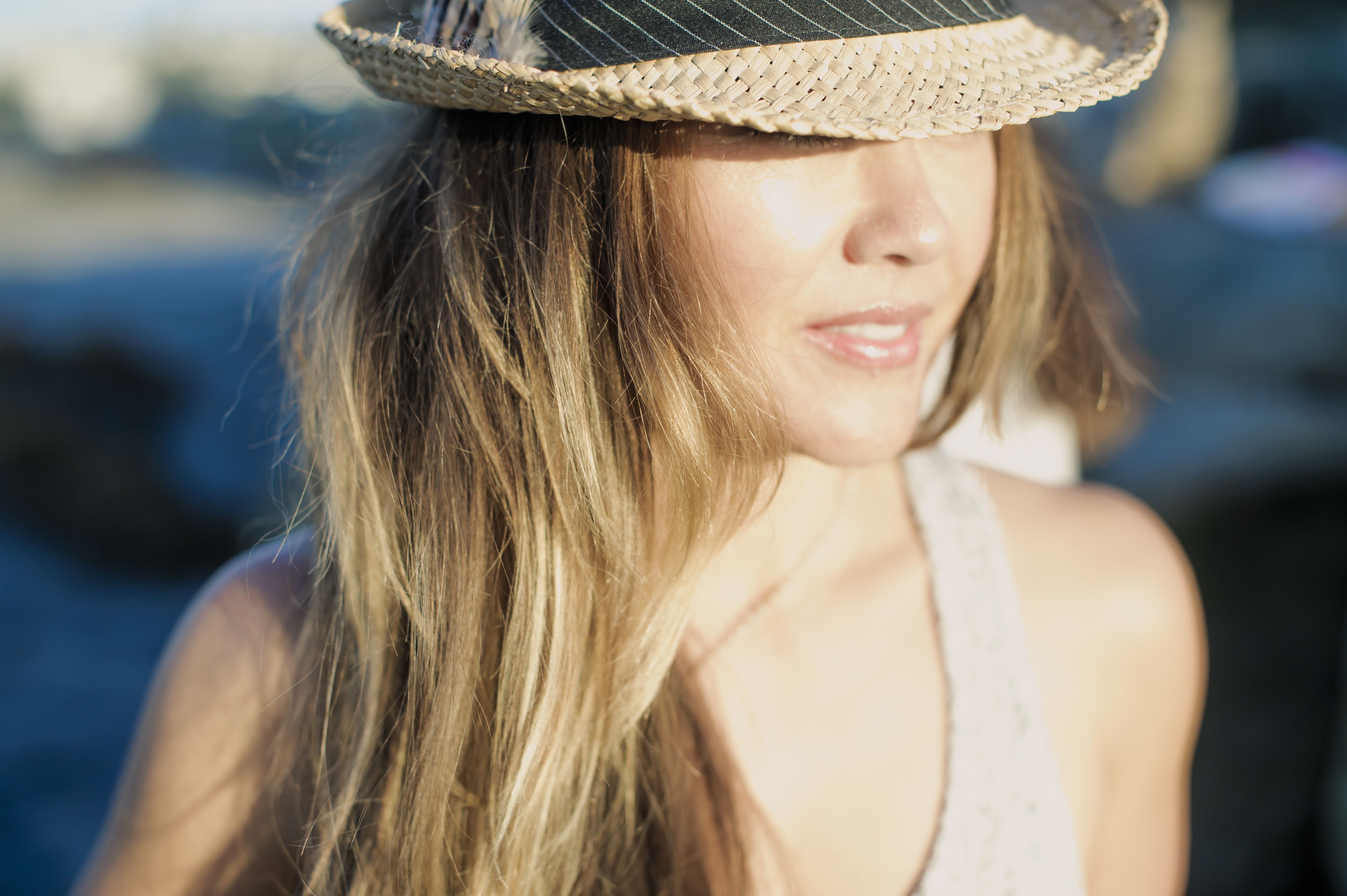 Donna con un grande cappello estivo, che evoca l'attrazione, il fascino di una prima impressione e il desiderio di vivere un incontro autentico.