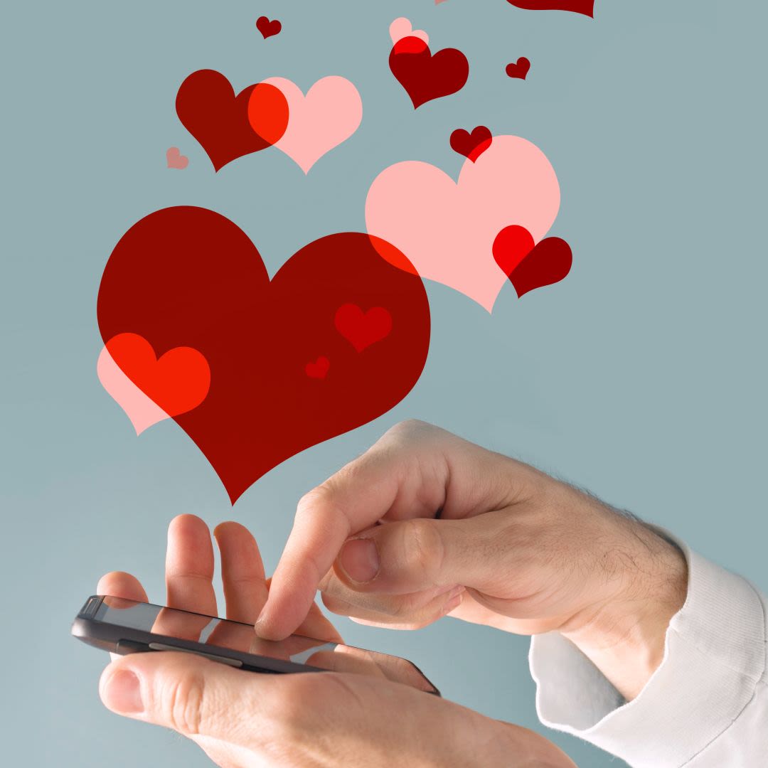 La mano di un uomo che usa uno smartphone per cercare un sito di incontri serio, con cuori illustrati a simboleggiare un incontro serio e una relazione duratura.