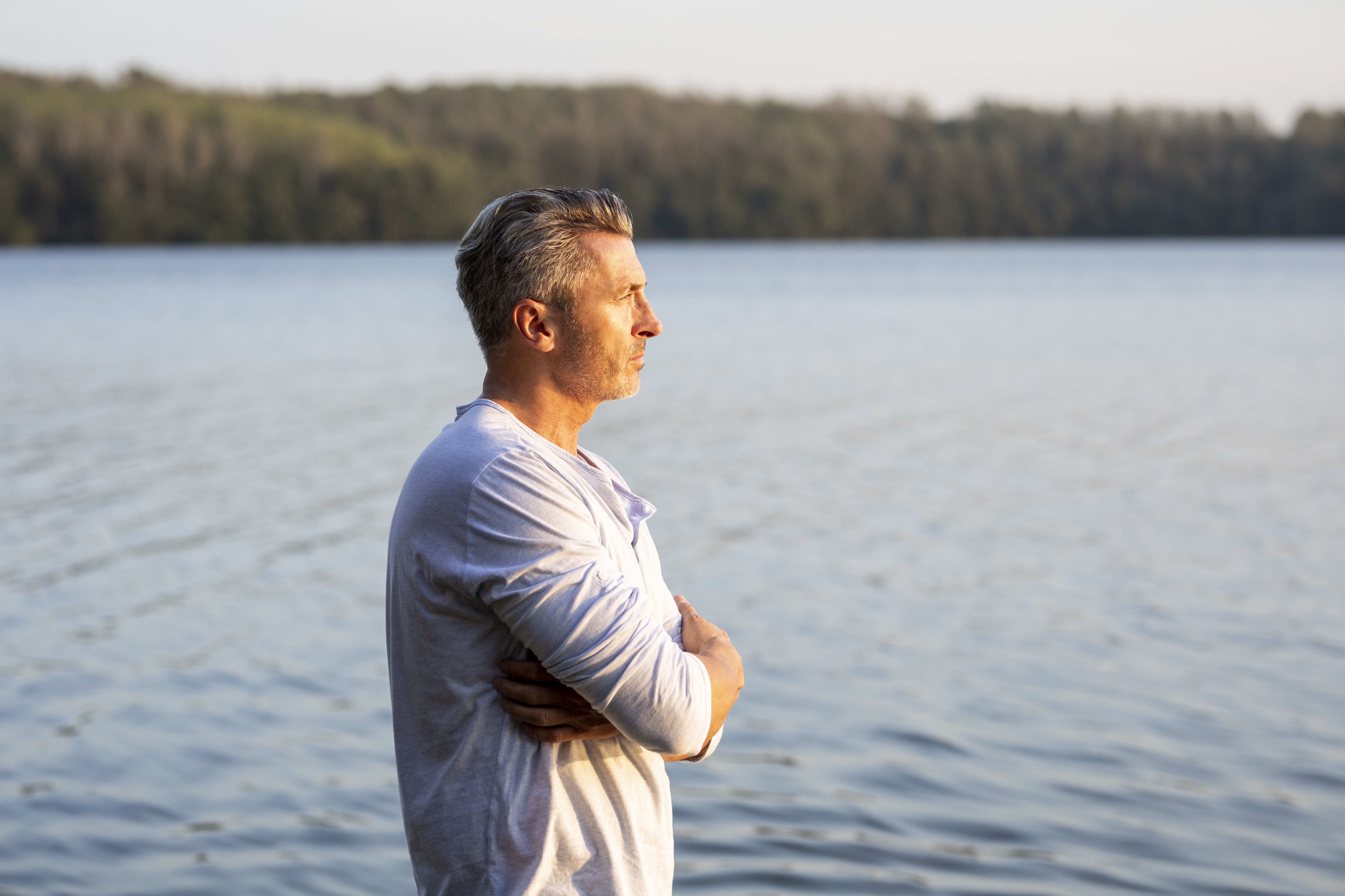 Uomo sulla cinquantina che contempla un lago con serenità, a illustrare un nuovo inizio e la ricerca di una relazione seria dopo un divorzio.
