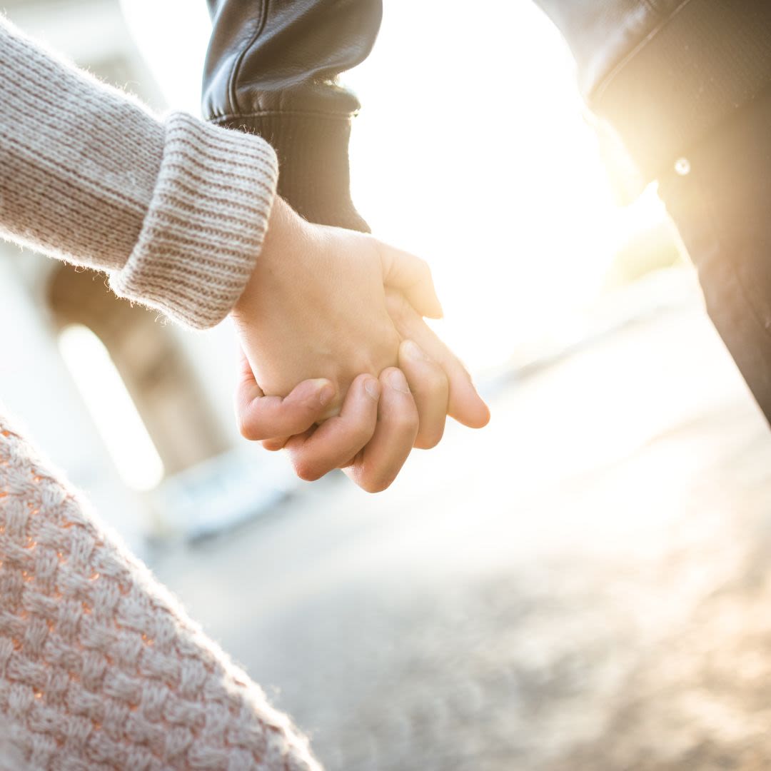 Una giovane coppia cammina mano nella mano alla luce del sole e condivide valori comuni per una relazione duratura.